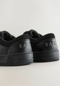 Schwarze Sneakers mit einem glatten Leder-Obermaterial, Mesh-Akzenten und einer strukturierten Gummisohle. Auf der Rückseite ist der geprägte Markenname "BAKE" zu sehen.