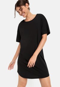 Zwart T-shirtjurk, korte mouwen, losse pasvorm, zacht materiaal, ronde halslijn en iets gebogen zoom, geschikt voor casual draagstijl.