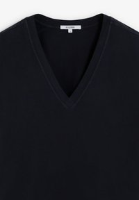 Camiseta de algodón negra con diseño de escote en V, que presenta una textura suave y sutiles acentos de costura. La etiqueta de tamaño indica pequeña (S).