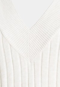 Maglione lavorato a maglia color crema con scollo a V, caratterizzato da una texture a costine verticali e un ampio colletto morbido.