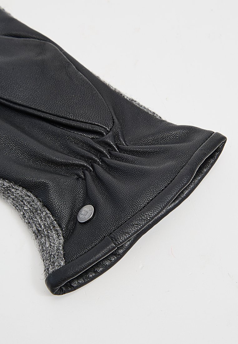 Schwarzer Lederhandschuh mit einem grauen Wollbund. Verfügt über gerafften Stoff am Handgelenk und ein kleines Metallschlißdetail für den Verschluss.