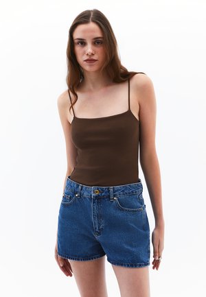 Bruine geribde tanktop met dunne bandjes, gecombineerd met hoge blauwe denim shorts met voorzakken en een sluiting met gouden knopen.