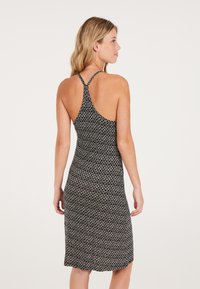 Vestido midi con estampado en blanco y negro, diseño de espalda al aire, tela suave y silueta ajustada, con una textura lisa y un sutil brillo.