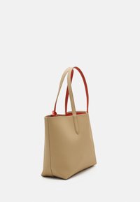 Geantă tote bej cu o formă structurată, textură netedă și mânere roșii contrastante. Prezintă un design minimalist și un capac deschis.