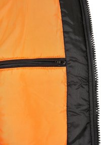 Intérieur de veste noire avec une doublure lisse et orange vif, une poche zippée, texture matelassée et coutures contrastantes.