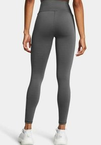 Grijze high-waisted tights gemaakt van gladde, rekbare stof, met een strakke pasvorm en naadloze constructie, gecombineerd met witte sneakers.
