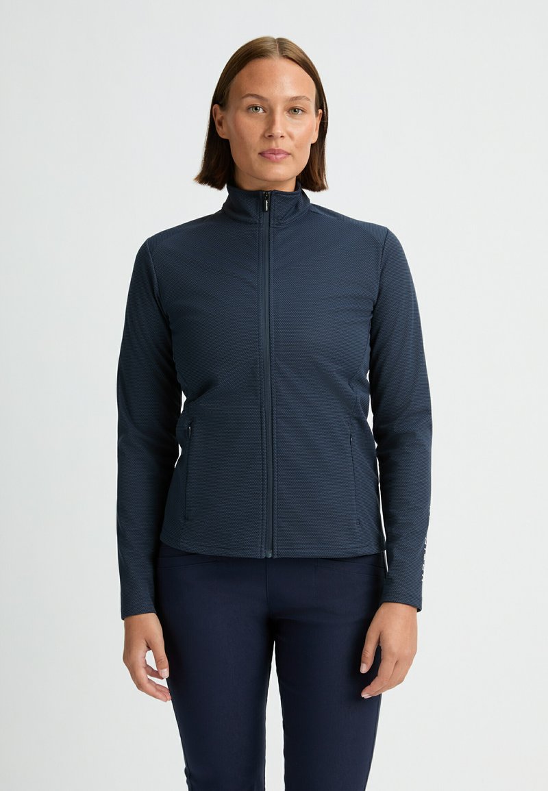 Giacca zip-up blu navy realizzata in tessuto testurizzato, con colletto alto, maniche lunghe e tasche laterali. Dettaglio logo discreto sulla manica.