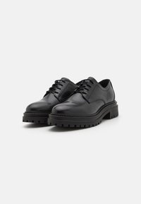 Chaussures en cuir noir avec des bouts arrondis, un laçage traditionnel et des semelles en caoutchouc robustes dotées de rainures prononcées pour une meilleure adhérence.