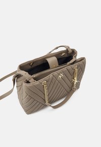 Sac à main taupe matelassé avec des anses en chaîne dorée, poche zippée, ainsi que des détails en logo et en charme dorés, ouvert pour montrer la doublure intérieure noire.