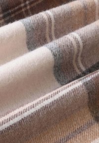 Tessuto in misto lana con un morbido motivo a quadri beige, marrone e grigio; presenta una consistenza soffice con sottili righe e pieghe sovrapposte.