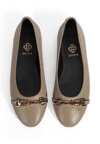 Beige Leder Ballerinas mit runder Spitze, minimaler Naht und einer goldfarbenen Schnalle vorne. Schwarzes Innenfutter.