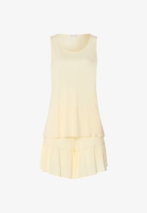 Ærmeløs, lys gul top med rund hals kombineret med matchende løse, flæsebesatte shorts.