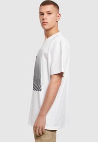 Hvid bomulds-T-shirt med korte �ærmer, prydet med et sort grafisk design af vandrette striber på forsiden. Klassisk crew neck-design.