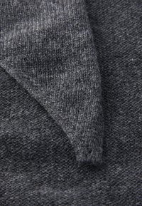 Gray knitted fabric showcasing fine and coarse textures, with a visible seam and an angled edge for design detail.