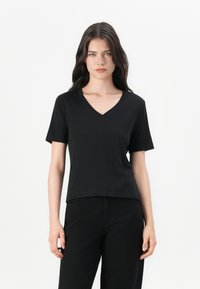 Black V-neck t-shirt with short sleeves, smooth texture, relaxed fit, and stitched finishing, paired with black pants. Clean, minimal design.