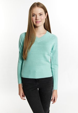 Pulover mint green, cu mâneci lungi, cu decolteu în V și margine ribbed. Prezintă o textură moale tricotată și o siluetă ajustată. Asortat cu blugi negri.