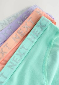 Culottes en coton coloré dans des teintes menthe, pêche, lavande et gris clair, chacune avec une taille pailletée argent "NEXT".