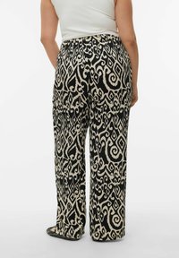 Pantalon à jambes larges avec un motif tourbillonnant noir et crème. Le tissu a une texture lisse. Taille élastique sans ornements visibles.