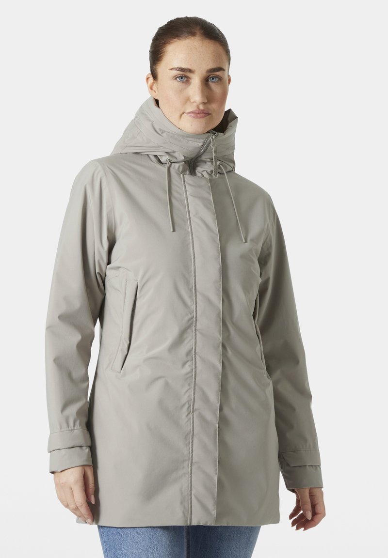 Chaqueta impermeable de color gris claro con un alto cuello, cordones ajustables y bolsillos laterales. Textura suave y diseño de ajuste relajado.
