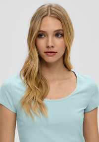 Helles blaues Baumwoll-T-Shirt mit kurzen Ärmeln und rundem Ausschnitt. Glatte Textur und einfaches Design ohne zusätzliche Muster oder Akzente.