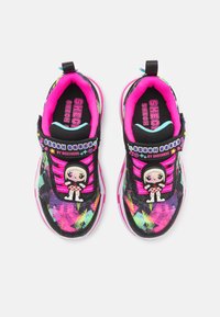 Skechers tornacipő fekete és színes mintázattal, rózsaszín részletekkel, rugalmas pántokkal és díszítő karakterrel a nyelvén.