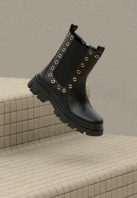 Stivaletto nero in materiale lucido, con pannelli laterali elasticizzati, occhielli dorati e suola spessa e robusta. Design semplice e moderno.