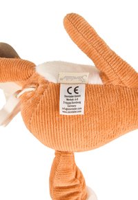 Soft stuffed animal with an orange corduroy texture, white fur accents, and a tag featuring care instructions and manufacturer details.