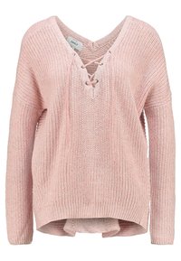 Maglione lavorato a maglia di un rosa chiaro con scollo a V, dettagli con lacci, texture a coste e maniche lunghe. Presenta un orlo posteriore più lungo.