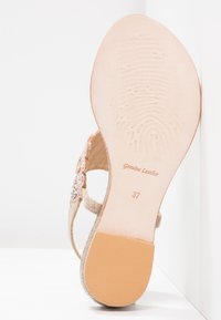 Podeszwa sandała z jasnoróżowym skórzanym dnem z wzorem odcisków palców, tekst "Prawdziwa skóra", rozmiar 37 oraz teksturowana gumowa łatka na pięcie.