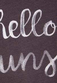Crni materijal s bijelim natpisom "Hello Sunny" u rukopisnom fontu, s mekanom teksturom i glatkom završnom obradom.