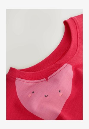 Rød bomulds-T-shirt med en pink hjertegrafik med et smilende ansigt. Ribket krave og blød tekstur med kontrastfarvede detaljer.