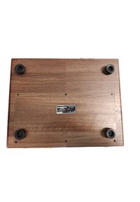 Base en bois avec une finition lisse en noyer foncé ; comporte quatre pieds en caoutchouc noir et une étiquette au centre.