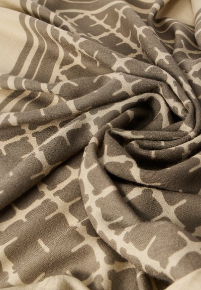 Υφασμα μπεζ με σχέδιο και υφή, που παρουσιάζει ένα μείγμα από σκούρα καφέ σχήματα που μοιάζουν με το παλτό καμηλοπαρδάλου σε μια ρέουσα διάταξη.