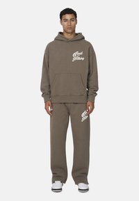 Brązowy bawełniany hoodie i dopasowane spodnie dresowe z białą grafiką "Good for Nothing". Luźny krój z przednią kieszenią i ściągaczami.