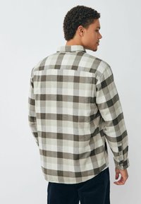 Koszula flanelowa w kratę w kolorze szarym i kremowym. Posiada długie rękawy, mankiety na guziki oraz prosty dół. Miękka tekstura z klasycznym wzorem.