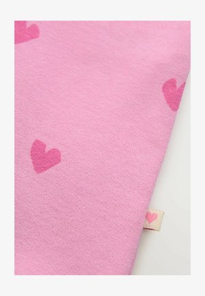 Rožinė medžiaga su minkštu tekstūru, išmėtytos širdelių detalės. Krašte matomas mažas ženkliukas su širdies akcentu.