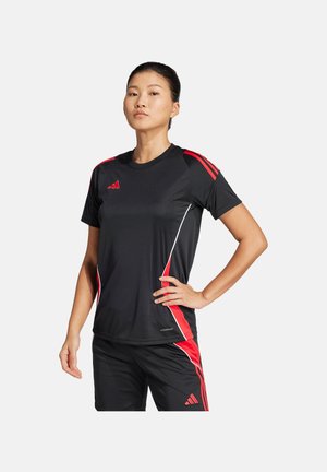 Schwarzes Sportshirt mit roten Akzenten und weißen Paspeln; verfügt über kurze Ärmel und das Adidas-Logo auf der Brust und der Schulter. Kombiniert mit schwarzen Shorts.
