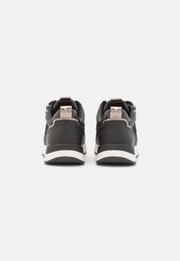 Scarpe da ginnastica nere con una tomaia testurizzata, accenti di colore duale, una suola intermedia spessa bianca e dettagli metallici sul tallone.
