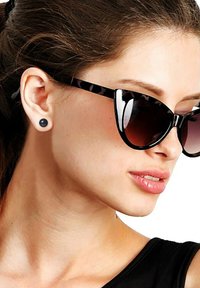 Zwarte cat-eye zonnebril met luipaardprint accenten, donkere glazen en ronde zwarte studs. Gelijkmatige huid met een subtiele glans.