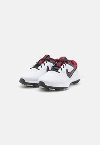 Baltos golfo bateliai su raudonais ir juodais akcentais, tinklinė viršutinė dalis, perforuotas dizainas kvėpavimui, ir balta smeiginių padanga stabilumui.