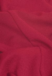 Roter Stoff mit einer weichen, glatten Textur, der ein drapiertes, leicht gekräuseltes Muster und eine einheitliche Farbe aufweist.