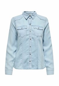 Camisa de mezclilla azul clara con mangas largas, cierre de botones, cuello apuntado, dos bolsillos en el pecho y detalles de costura sutiles. Tejido texturizado.
