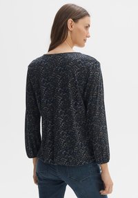 Marineblaue Bluse mit langen Ärmeln und einem strukturierten Muster in Blau- und Grüntönen, mit rundem Ausschnitt und lockerer Passform sowie elastischen Bündchen.