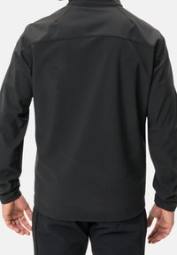 Veste noire imperméable avec une texture lisse, une silhouette ajustée, un col haut et un design minimaliste. Vue de dos avec des manches longues.