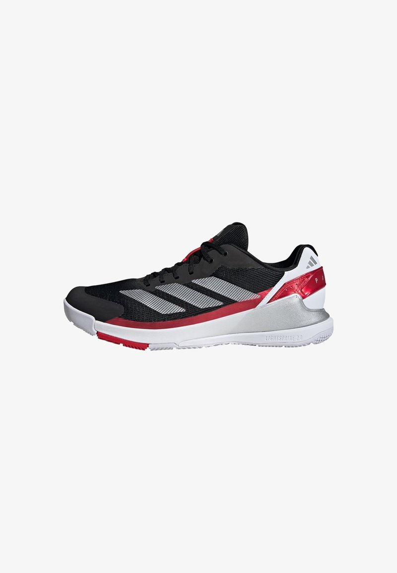 Chaussure de sport noire avec un dessus en maille, des rayures argentées, des accents rouges et une semelle blanche. Dispose d'un talon rembourré et d'une semelle extérieure texturée.