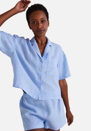 Chemise en lin bleu clair à manches courtes avec des boutons et une poche, assortie à un short. Texture douce, coupe décontractée, design casual.