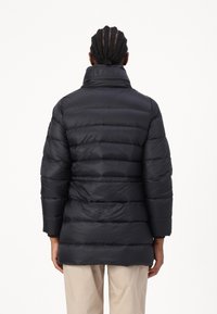 Black puffer jacket with a high collar, horizontal quilted texture, and subtle logo on the collar. Designed for warmth and comfort.