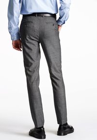 Pantaloni grigi slim-fit con un tessuto strutturato, due tasche posteriori e una cintura nera, abbinati a una camicia azzurro chiaro con bottoni.