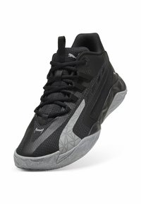 Chaussure de sport noire avec une tige synthétique texturée, des accents gris, et une semelle à motifs. Comprend un laçage et un détail de logo sur la languette.