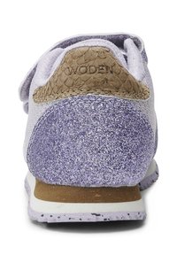 Sneakers viola con una texture glitterata, tomaia in suede e un accento marrone con motivo rettile sul tallone. Suola bianca con alcune macchie.